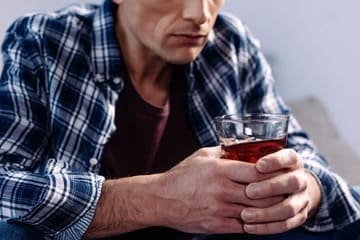 Мужчина держит в руках стакан с алкоголем